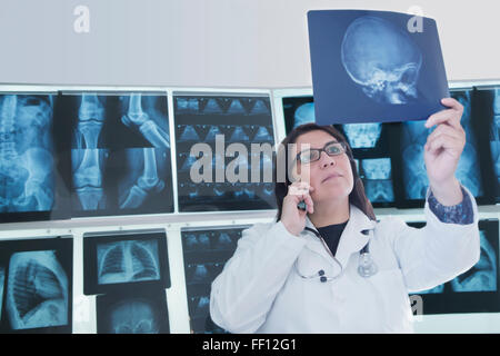 Hispanic doctor examining x-rays in hospital Stock Photo