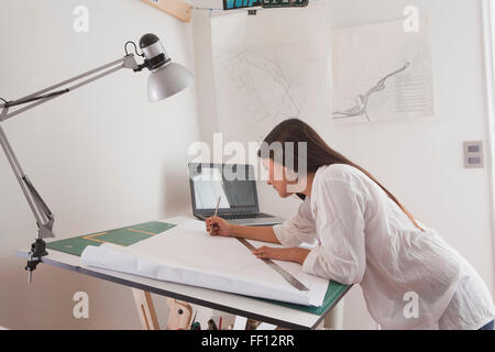 Hispanic architect drawing at drafting table Stock Photo