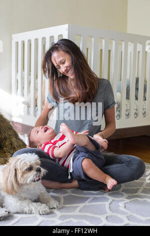Mixed race mother playing with baby in nursery Stock Photo