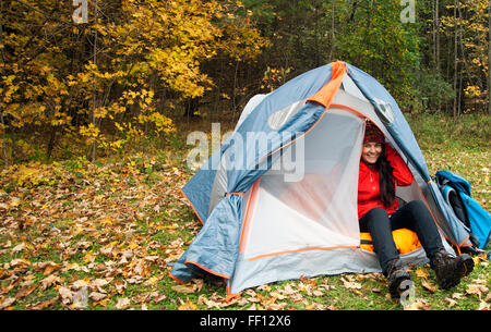 Hiker sitting in tent at campsite Stock Photo