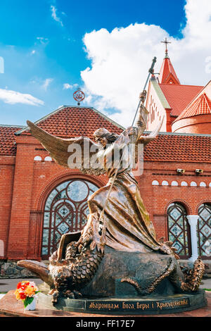 Statue of Archangel Michael with outstretched wings, thrusting spear into dragon before Catholic Church of St. Simon and St. Hel Stock Photo