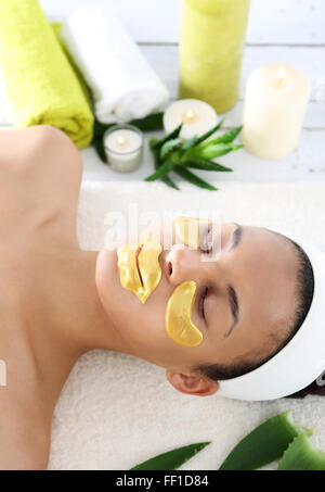 Cosmetic procedure, the woman's face with gold flakes under the eyes and on the lips Stock Photo