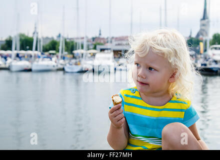 Little girl eating ice cream on a background of harbor Stock Photo