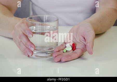 person holding various pills and glass of water Stock Photo