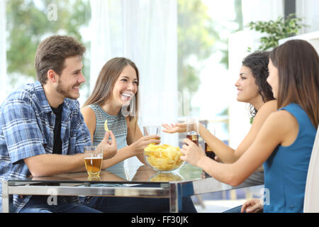Funny group of 4 friends having a conversation and drinking at home Stock Photo