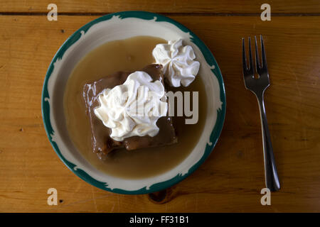 A sticky toffee pudding served in Nova Scotia, Canada. The pudding is served with sauce and cream. Stock Photo