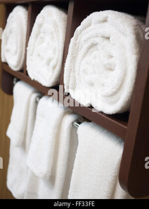Bathroom towel rack with rolled and hanging towels in a hotel bathroom Stock Photo