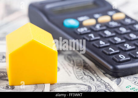 toy house and calculator on the background dollars banknotes Stock Photo