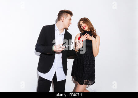 Attractive confident young man holding red box with ring and  making proposal to his girlfriend over white background Stock Photo
