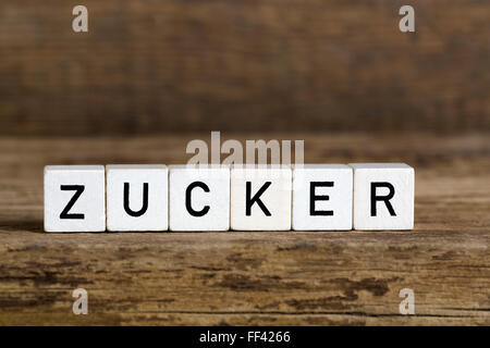 The German word sugar written in cubes on a wooden background Stock Photo