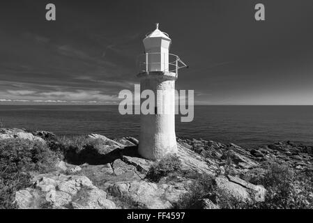 White lighthouse,blue sea and sky in bright sunlight at Stenshuvud National Park at the Baltic Sea coast in Skane, Sweden Stock Photo