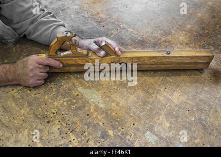 Carpenters hands hold planer tool on a vintage wooden background Stock Photo