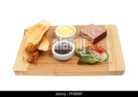 Farmhouse pate with toast, butter, red onion marmalade and salad on a wooden board isolated against white Stock Photo