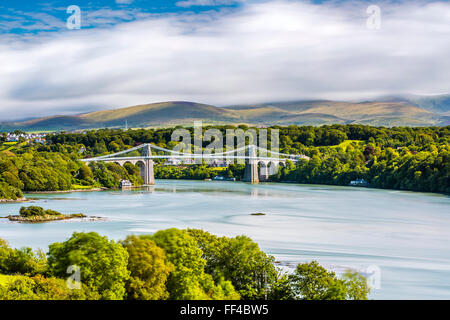 The Menai Suspension Bridge linking the island of Anglesey with mainland Wales, backed by the mountains of Snowdonia National Pa Stock Photo