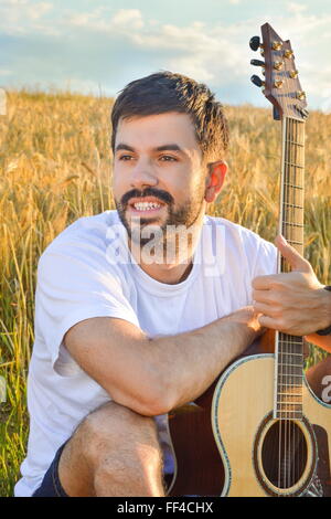 bearded boy with a guitar in thewheat  field Stock Photo