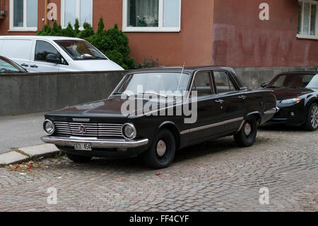 Black 1964 Plymouth Valiant 4-door sedan parked curbside on a street paved with setts. Stock Photo
