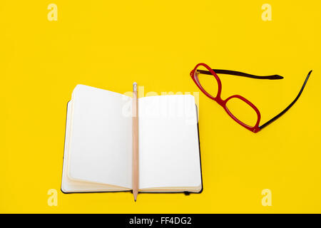 Eyeglasses and notebook isolated on yellow background Stock Photo