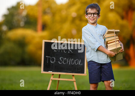 Cute little schoolboy carrying a stack of books Stock Photo