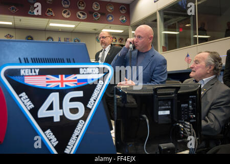 Former President George H.W. Bush, right, with former astronaut Mark Kelly as they speak with twin brother Expedition 46 Commander Scott Kelly and Flight Engineer Tim Kopra currently on the International Space Station from the Flight Control Room during a visit to the Johnson Space Center February 5, 2016 in Houston, Texas. Stock Photo