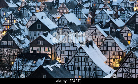 Dreamily scene of a winter village in germany with snow covered roofs at the early evening. Old town with half timbered historic Stock Photo