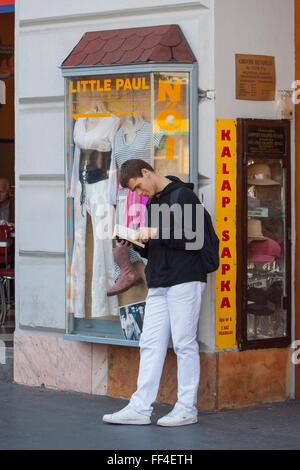 Student reading book and smiling while waiting for bus, Budapest, Hungary Stock Photo
