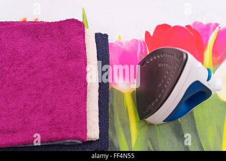 Electric iron and towels on ironing board Stock Photo