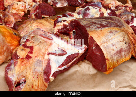 Large pieces of raw meat, beef, sit on a warm open air counter in a market in Kampala, Uganda. Stock Photo