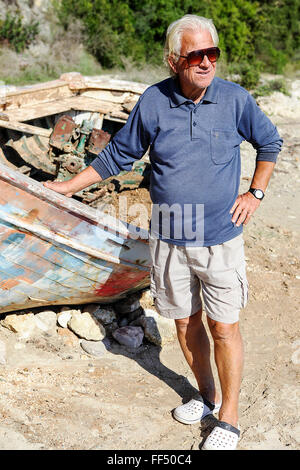 Traditional Greek fisherman's boat slowly rots away through neglect and Ferry Captain on Valtos beach in Greece. Stock Photo