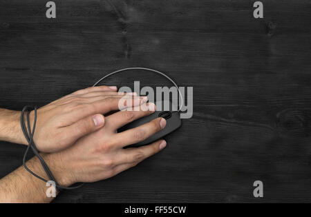 Bound wrist by computer mouse cable, on black background Stock Photo