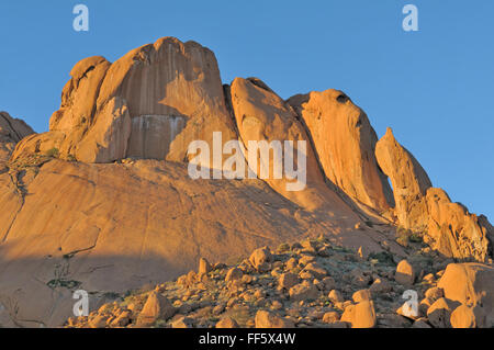 Rock formations resembling a falcon, shark and baboon at Spitzkoppe in Namibia at sunset. The sandstone becomes a deep orange Stock Photo