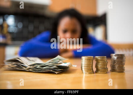 A young lady sits at her kitchen table counting her money to pay the household bills. Stock Photo