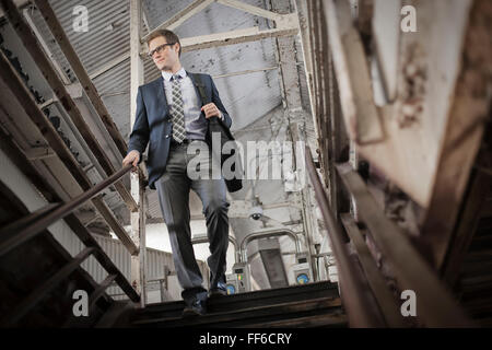 A working day. Businessman in a work suit and tie walking down stairs in a public space.