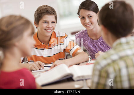 A group of students seated at a desk in a lesson talking to each other. Stock Photo