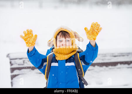 Cute little boy, catching snowflakes in the park on a winter day, heavy snow Stock Photo