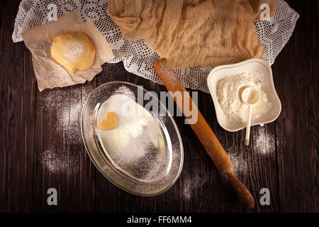 cooking biscuits in the shape of a heart on a wooden brown background, flour, rolling pin, the concept of Valentine's Day Stock Photo