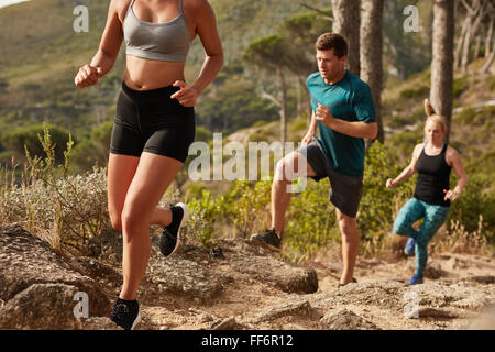 Fit young people running up a hill. Trail running training. Young and fit athletes running cross country. Stock Photo