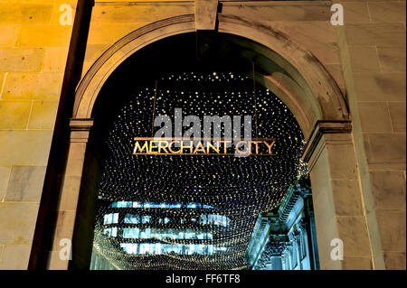 The Merchant City sign in Royal Exchange Square, Glasgow city centre, lit up at night against a twinkling backdrop. Stock Photo