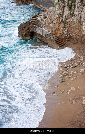 Staircase on a little beach around a steep rock wall, connecting two beaches on the Mediterranean Sea, Monte Carlo, Monaco Stock Photo