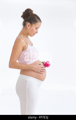 pregnant asian woman with a rose in hands on her belly, isolated against white background Stock Photo