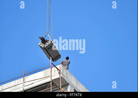 Unrecognizable construction worker guiding a construction crane loaded with materials Stock Photo