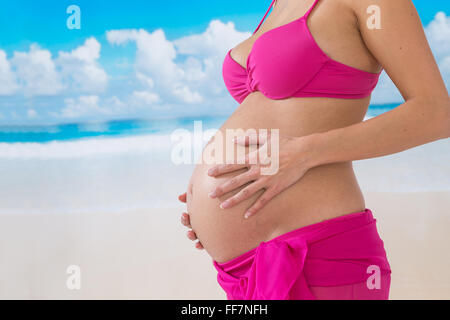 Beautiful Asian pregnant woman walking on blue beach in summer vacation Stock Photo