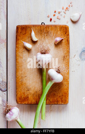 Still life of fresh garlic bulbs on an an old cutting board. Delicate arrangement in pastel colours. Stock Photo