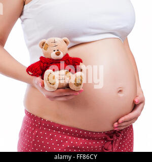 Pregnant mother showing her belly and holding a teddy Stock Photo