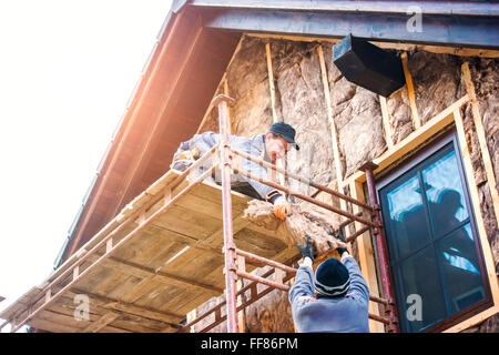 Construction workers thermally insulating house facade with glass wool. Stock Photo