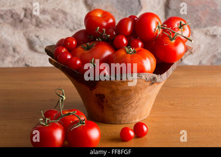 Big bowl of tomatoes sitting on a country kitchen table Stock Photo