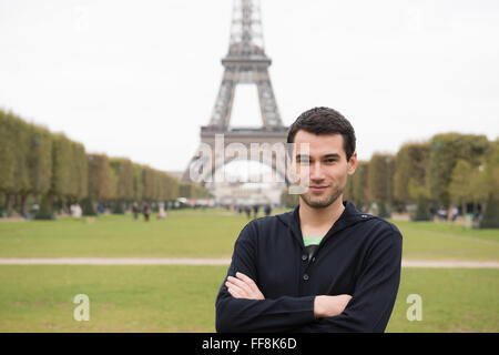 Young man standing in front of Eifel Tower in Paris, France, wearing black clothes Stock Photo