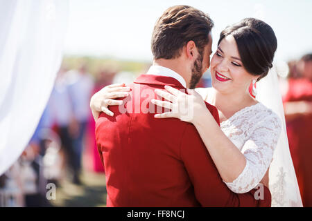 Bride and groom dancing at wedding ceremony on background of arch. Marsala color decoration style. Stock Photo