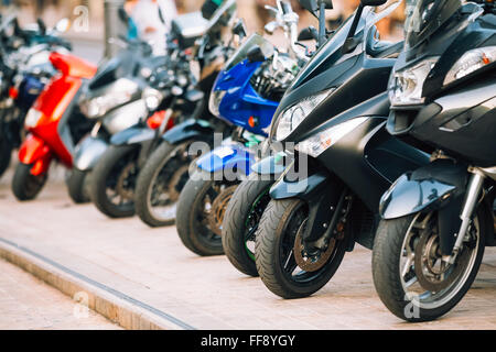 Motorbike, motorcycle scooters parked in row in city street. Close up of wheel Stock Photo