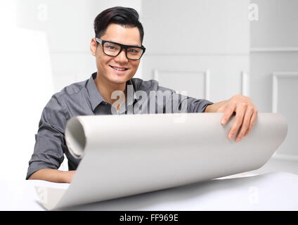 Handsome man while working on a project sitting behind a desk and watching the papers Stock Photo