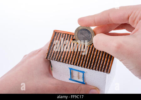 Hand dropping coin into the moneybox in the shape of a model house Stock Photo